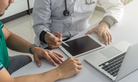 A doctor collecting information on a patient using various mobile devices