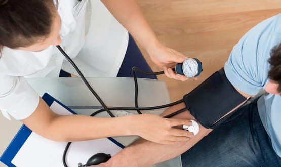 A female doctor performs a blood pressure test on a male patient