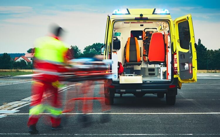 An out of focus shot showing a paramedic loading a stretcher into the back of an ambulance