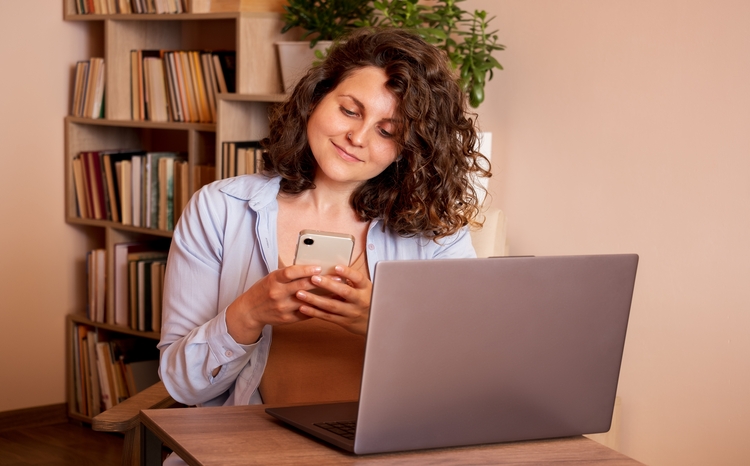 Young,Woman,Using,Laptop,And,Mobile,Phone,At,The,Working